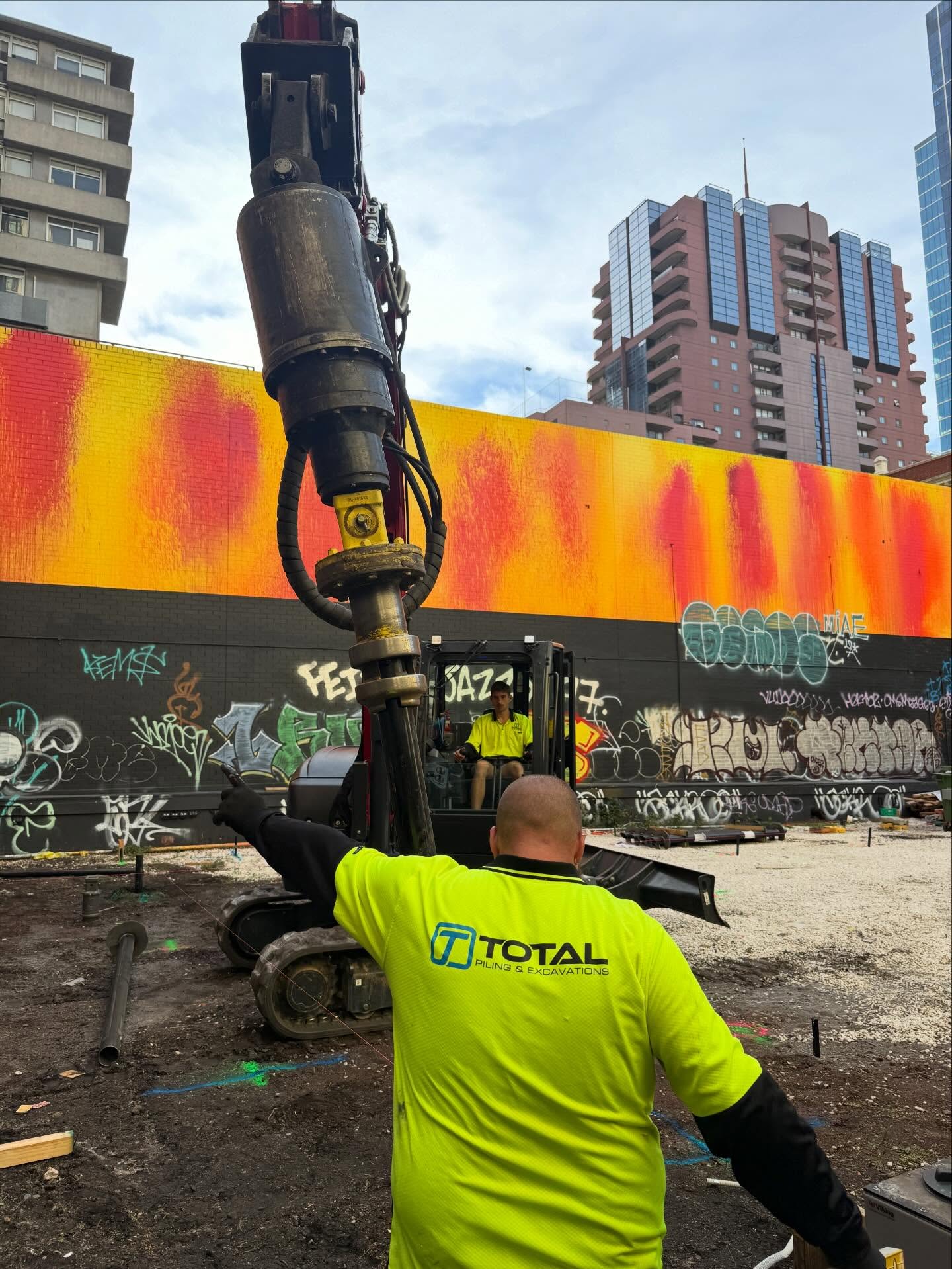 Total Piling team member operating a tracked screw pile drive motor on a Melbourne CBD site