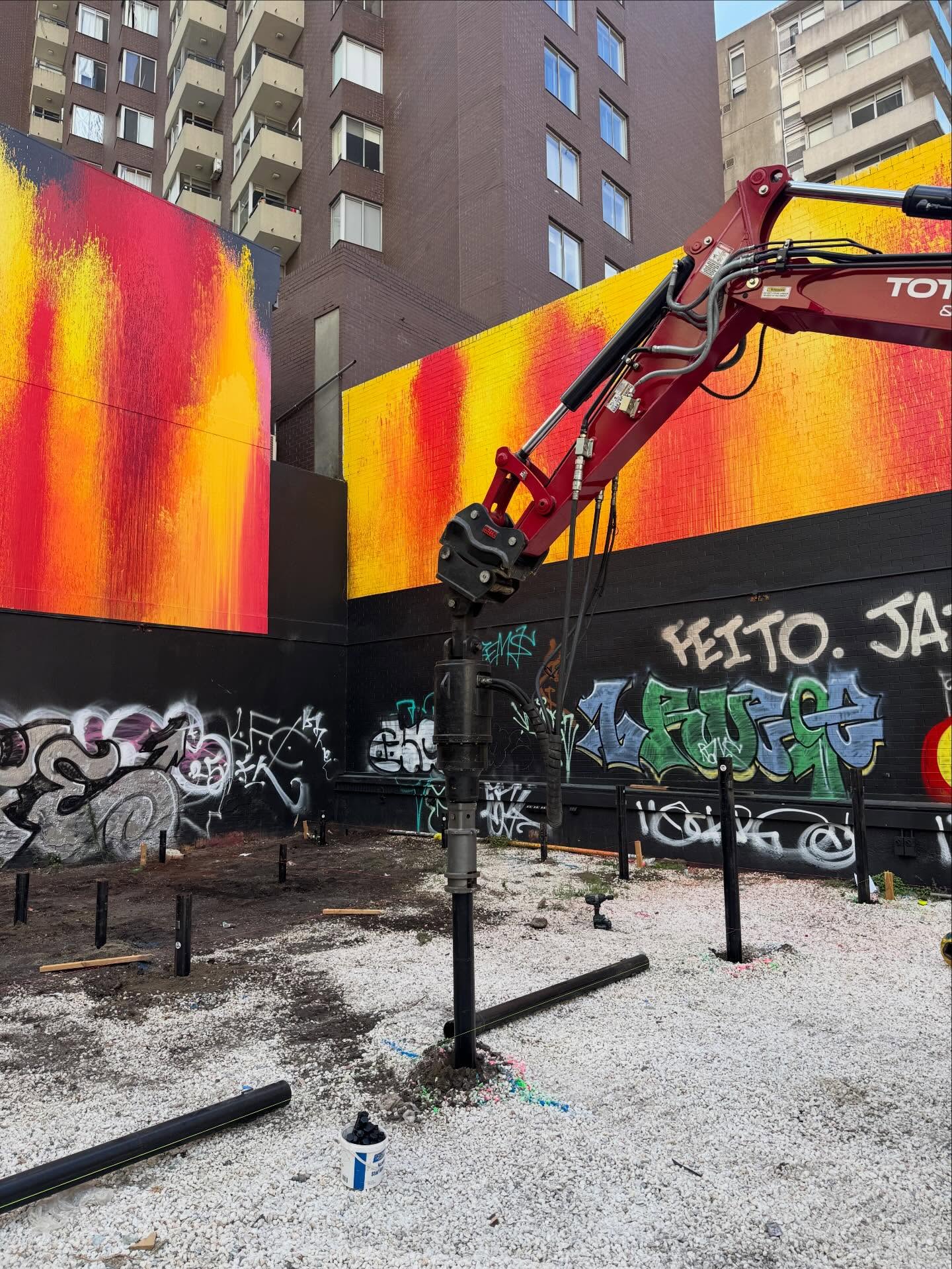 Total Piling excavator screwing piles at an urban infill site