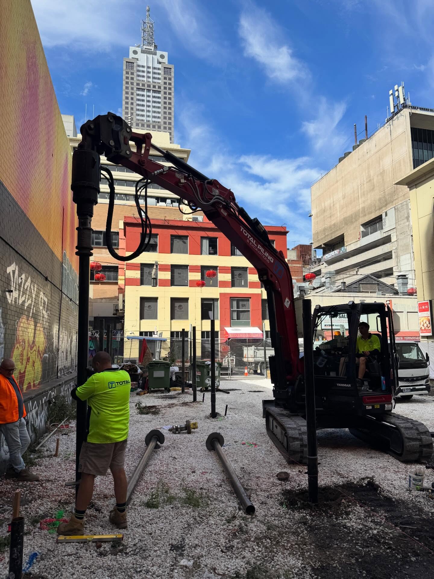 Branded Total Piling excavator drilling screw piles on a Melbourne CBD construction site