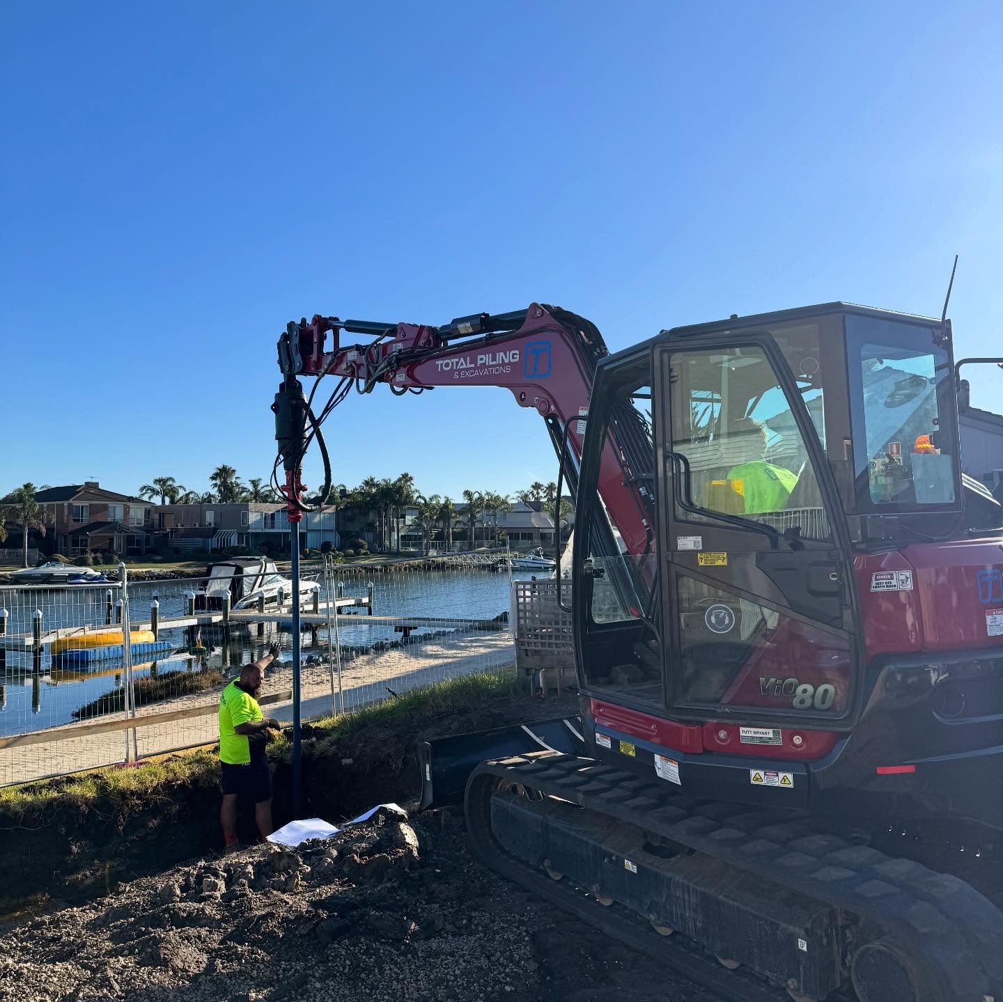 Total Piling branded excavator installing screw piles at a Victorian waterfront site