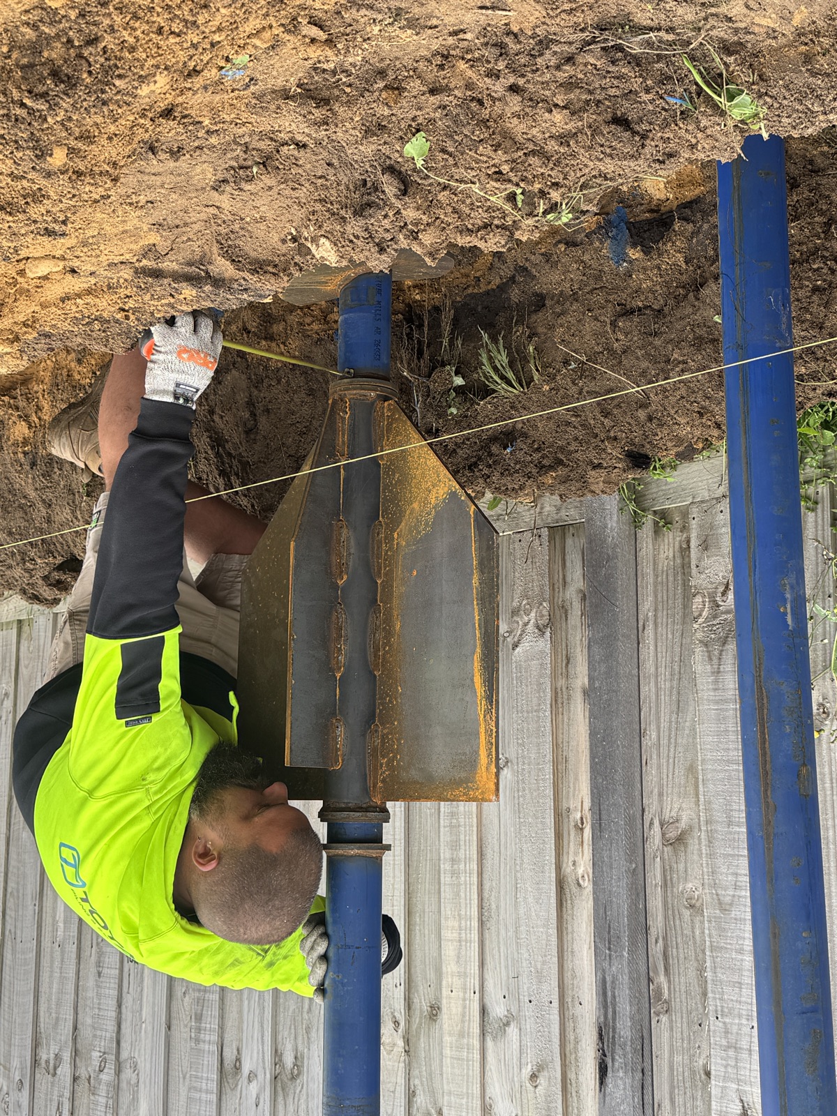 Total Piling worker installing a shoring panel against a timber boundary fence on a Victorian excavation