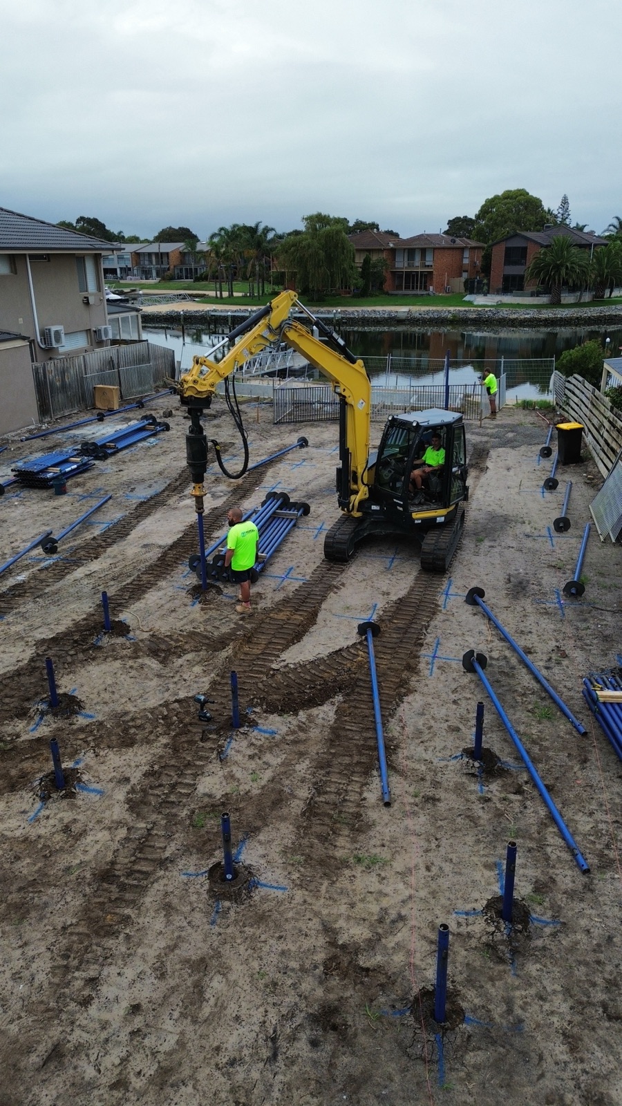 Total Piling branded excavator driving screw piles across a waterfront residential site in Victoria